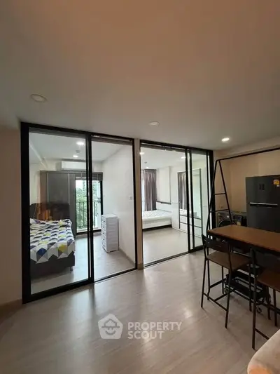Modern apartment interior with two bedrooms and open living area, featuring sleek glass partitions.