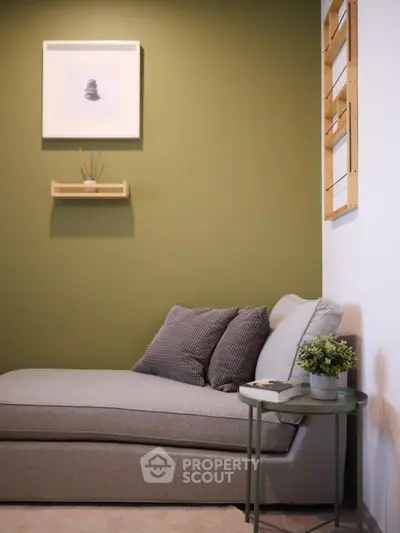 Cozy living room corner with stylish gray sofa and green accent wall.
