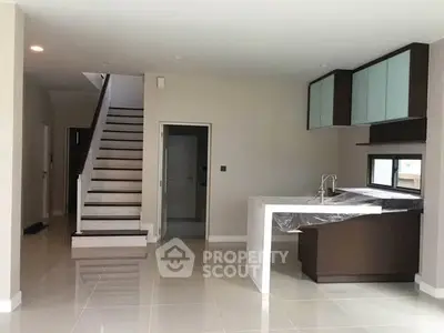 Modern open kitchen with sleek design and staircase in contemporary home interior.