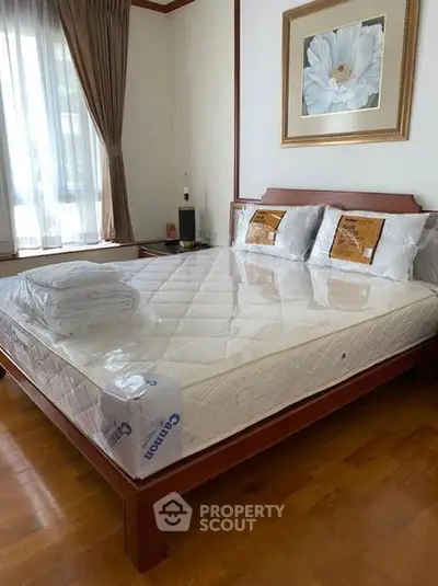Spacious bedroom with elegant wooden bed and large window for natural light.
