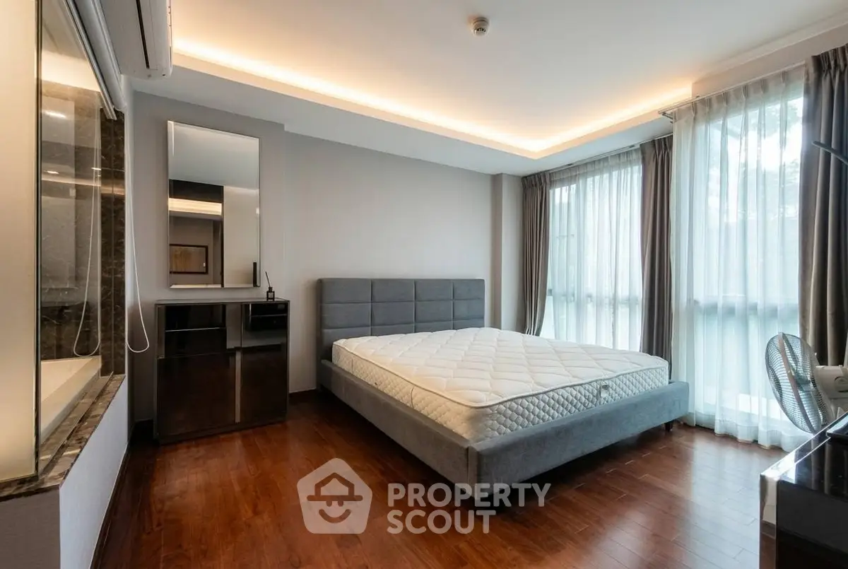 Spacious modern bedroom with large windows and elegant wooden flooring