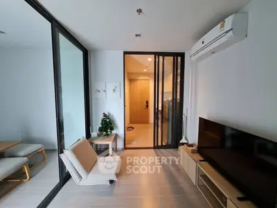 Modern living room with sleek design, featuring a TV unit, air conditioning, and sliding glass doors leading to a dining area.