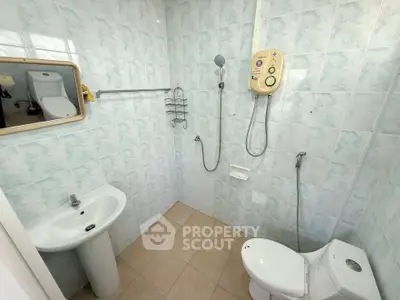 Compact bathroom with shower and toilet in tiled setting