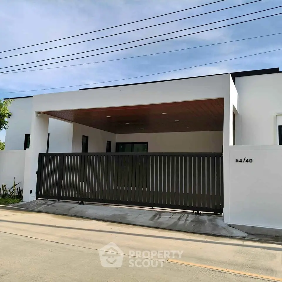 Modern minimalist house exterior with sleek gate and wooden ceiling accents.