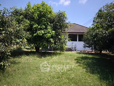 Charming house with lush garden and mature trees under a clear blue sky.