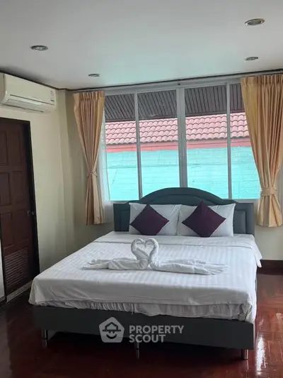 Cozy bedroom with large windows and air conditioning, featuring a stylish bed and elegant curtains.