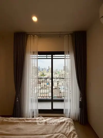 Cozy bedroom with city view through large window and elegant curtains.