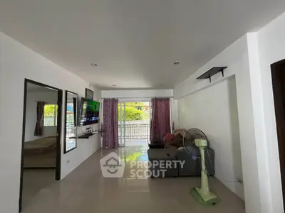 Spacious living room with modern decor and large windows leading to a balcony.