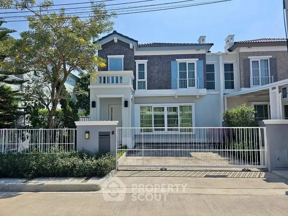 Charming two-story house with balcony and gated front yard in a serene neighborhood.