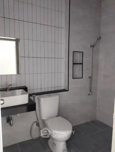 Modern bathroom with sleek design, featuring a toilet, sink, and shower area with stylish tiles.