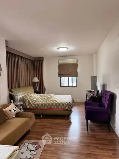 Cozy bedroom with stylish decor and wooden flooring, featuring a comfortable bed and elegant seating area.