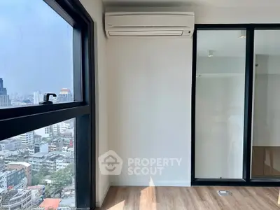 Modern apartment with large windows and city view, featuring sleek air conditioning unit and wooden flooring.