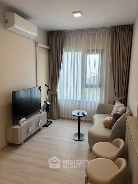 Modern living room with stylish furniture and large window offering natural light.