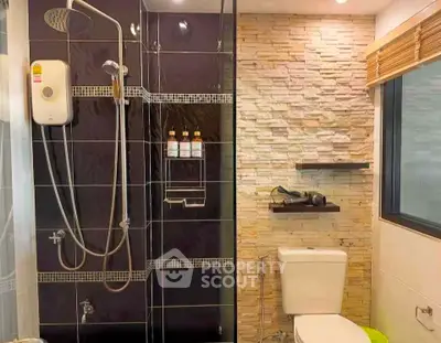 Modern bathroom with sleek shower and stone accent wall, featuring contemporary fixtures and natural lighting.