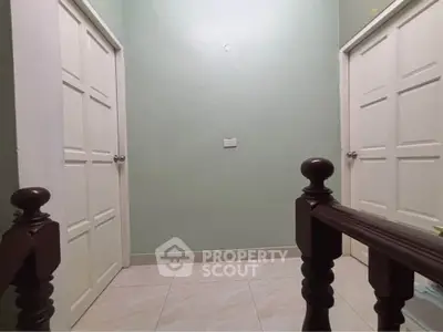 Simple hallway with two white doors and wooden railing