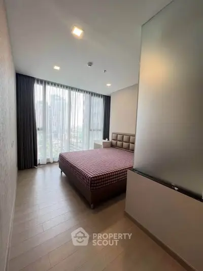 Modern bedroom with large window and stylish decor in a high-rise apartment.