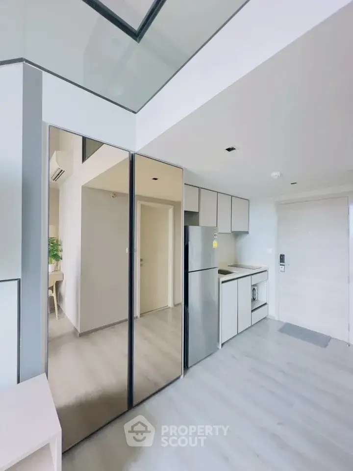 Modern minimalist kitchen with sleek design and stainless steel appliances in a bright apartment.