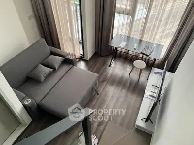 Modern living room with sleek gray sofa, large windows, and stylish decor in a contemporary apartment.