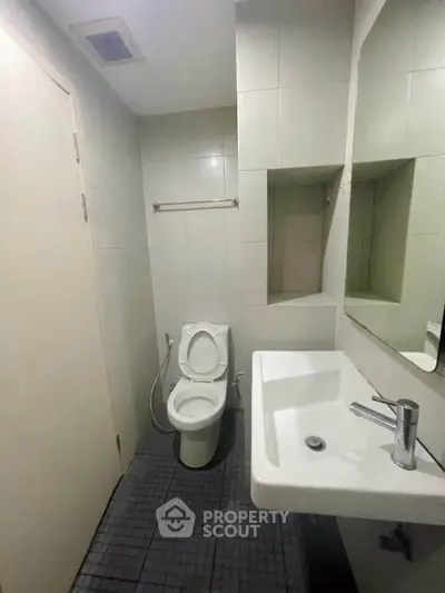 Compact bathroom with modern fixtures and tiled walls, featuring a sleek sink and toilet.