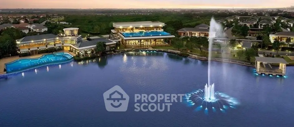 Luxurious lakeside property with stunning pool and illuminated fountain at sunset.
