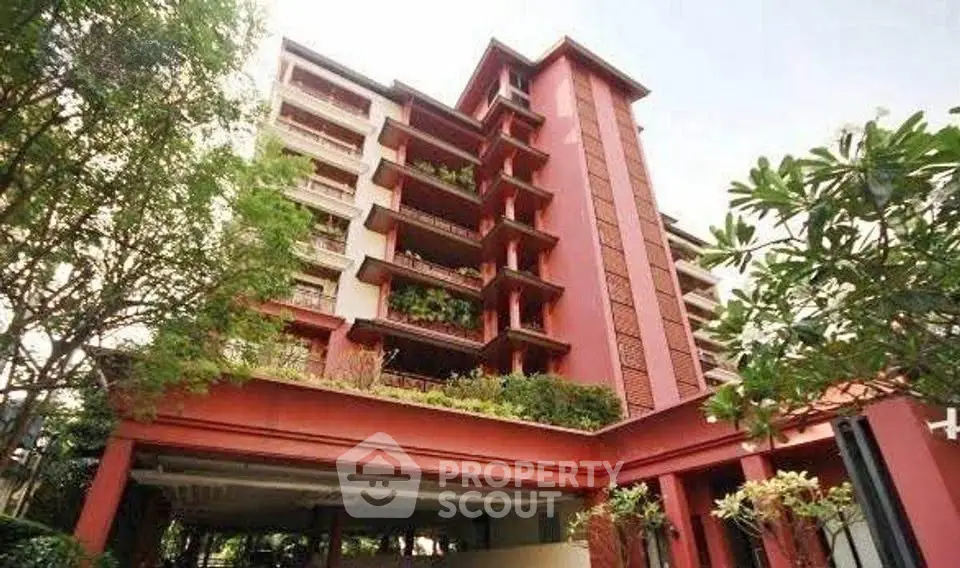 Stunning red building with lush greenery and spacious balconies