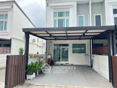 Modern townhouse with covered carport and potted plants in a residential area.