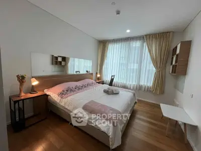 Spacious bedroom with elegant decor and large window for natural light.