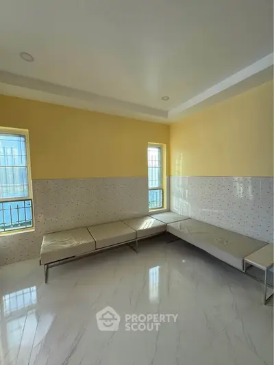 Spacious room with modern seating and large windows in a bright, airy setting.