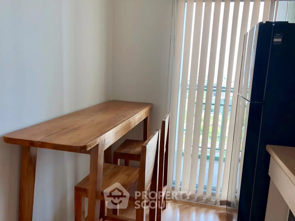 Cozy kitchen nook with wooden table and chairs, featuring natural light from vertical blinds.