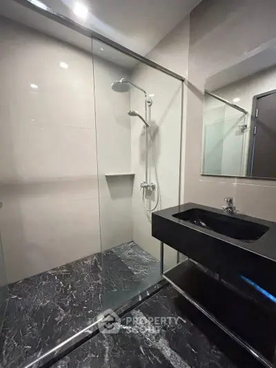 Modern bathroom with sleek black sink and glass shower enclosure