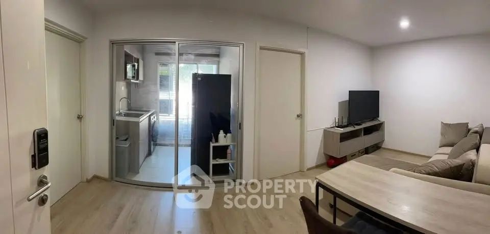 Modern living room with open kitchen and sleek furnishings in a cozy apartment.
