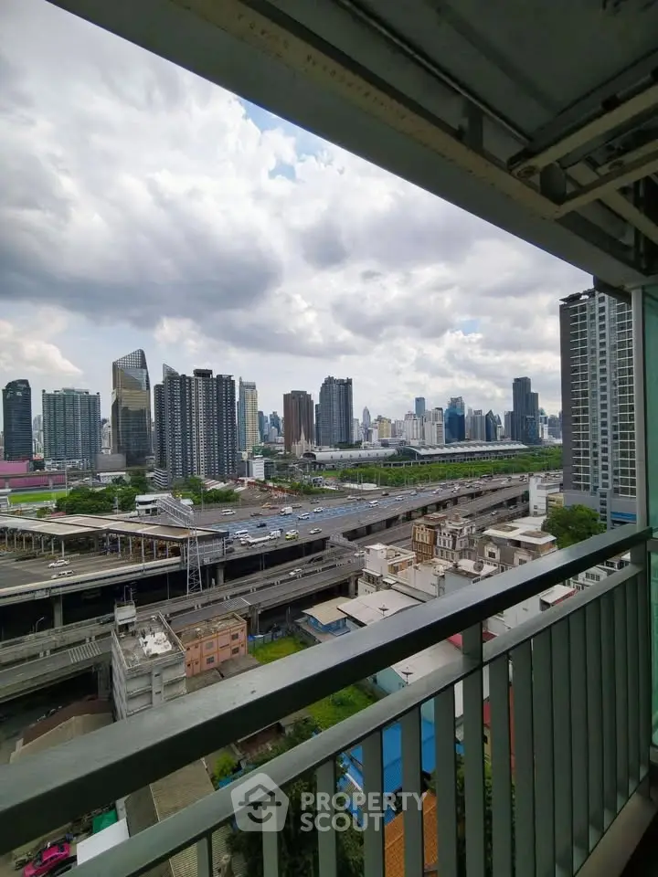 Stunning cityscape view from high-rise balcony overlooking urban skyline and highway.