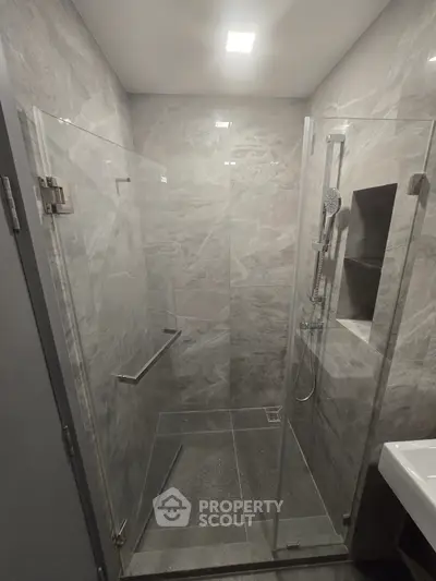 Modern bathroom with sleek glass shower enclosure and elegant gray tiles.