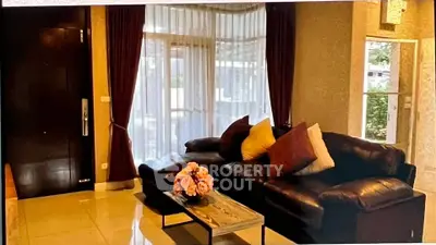 Cozy living room with leather sofa and large windows, perfect for relaxation.