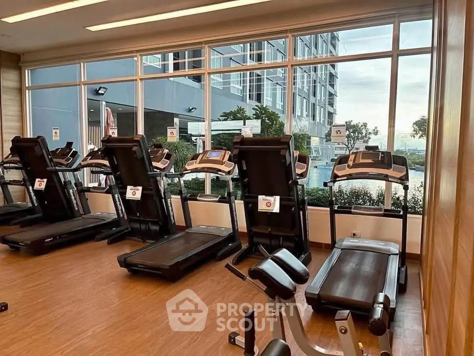 Modern gym with treadmills and large windows offering a scenic view of the cityscape.