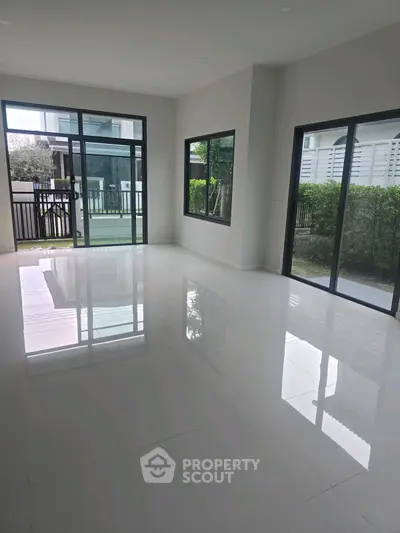 Spacious modern living room with large windows and glossy tile flooring.