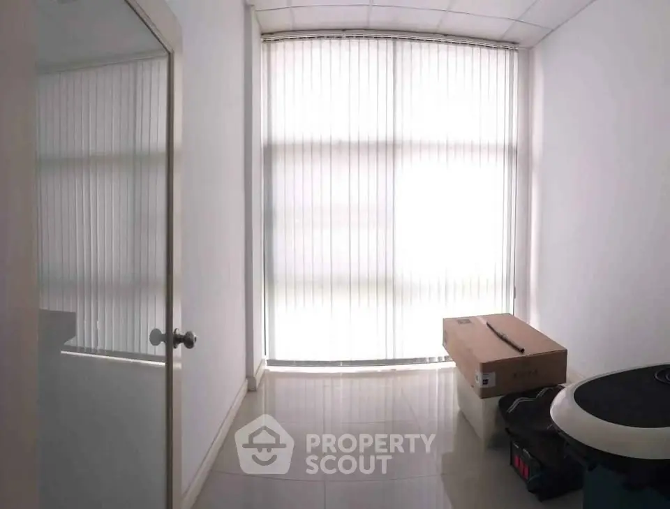 Bright room with large window and vertical blinds, ideal for office or study space.