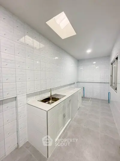 Spacious modern kitchen with sleek white tiles and ample counter space