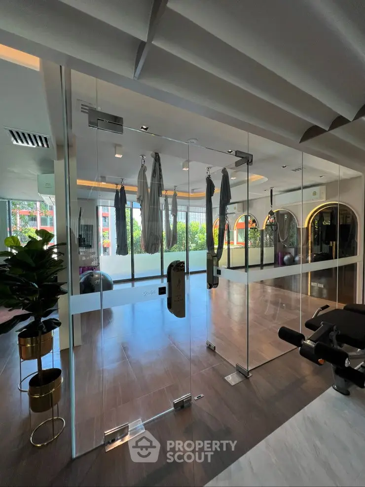 Modern gym with glass walls and aerial yoga setup, perfect for fitness enthusiasts.