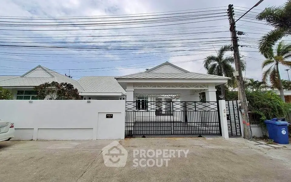 Charming single-story white house with gated entrance and palm trees