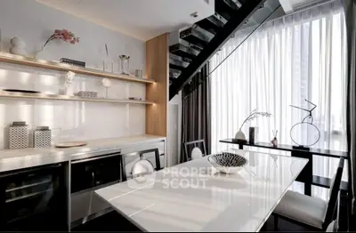 Modern kitchen with sleek design, open layout, and elegant dining area under staircase.