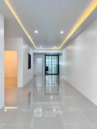 Spacious modern living room with sleek tile flooring and ambient ceiling lighting