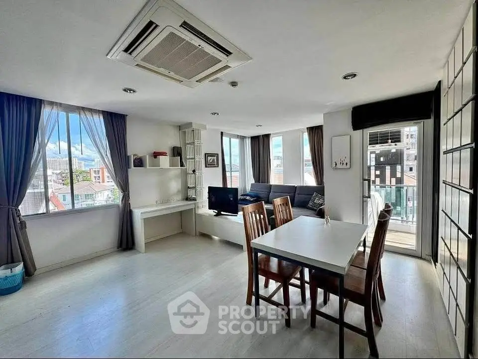 Spacious living room with dining area and large windows offering city views.