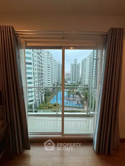 Spacious balcony view overlooking modern apartment complex with pool.