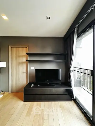 Modern living room with sleek TV stand and large window offering city views.