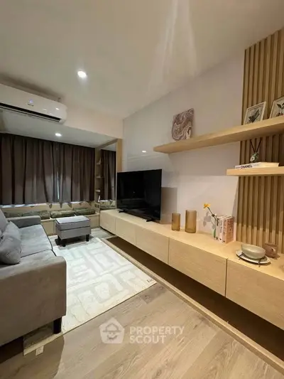 Modern living room with sleek furniture and large TV, featuring stylish decor and ample natural light.