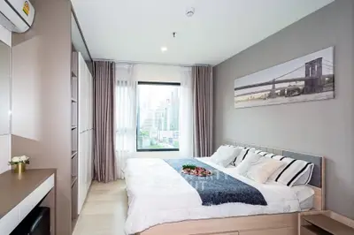 Modern bedroom with city view, stylish decor, and ample natural light
