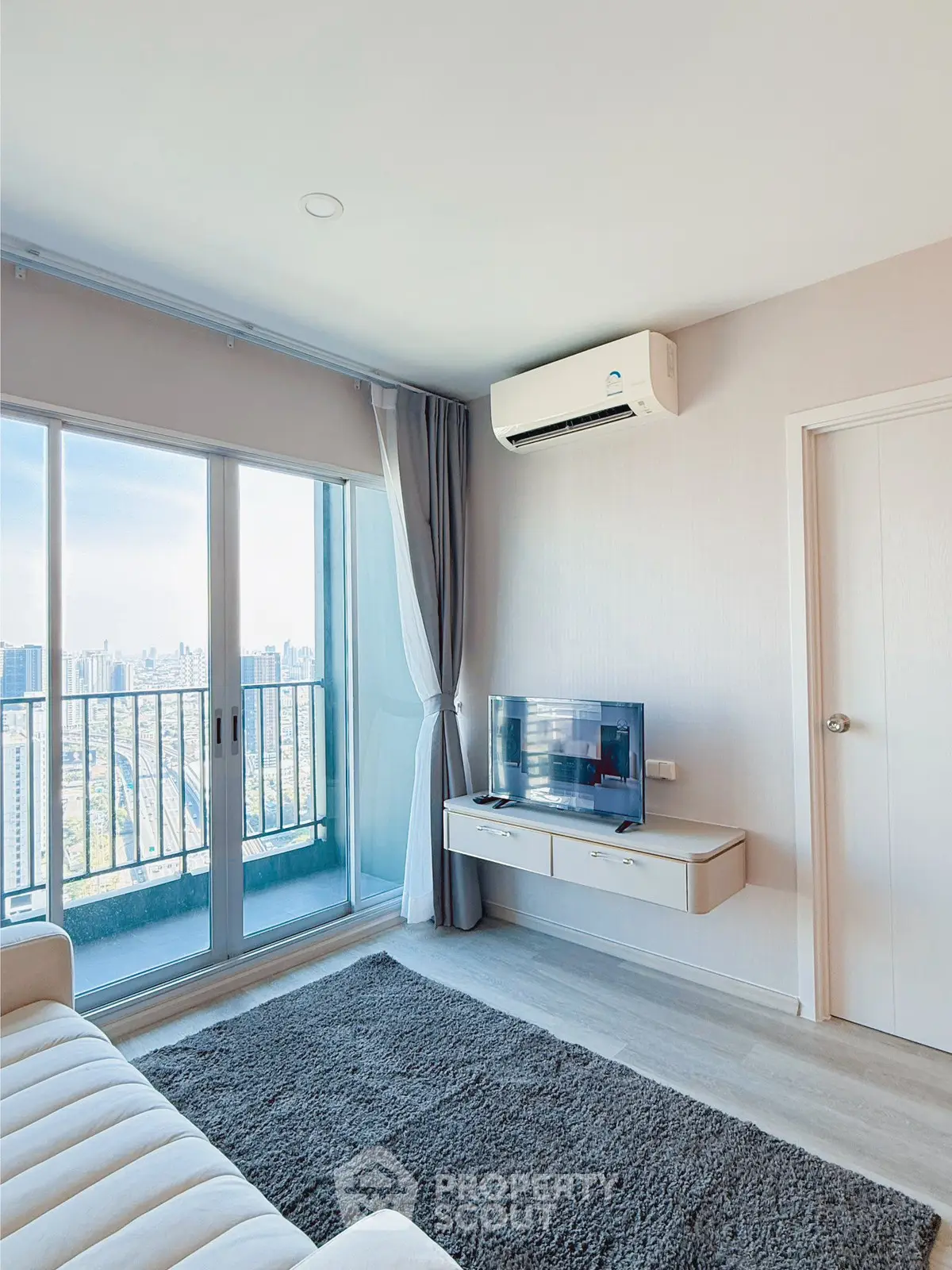 Modern living room with city view, featuring sleek furniture and large windows for natural light.