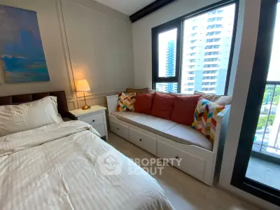 Cozy bedroom with large window and stylish seating area in modern apartment