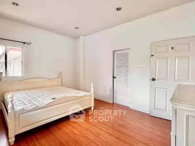 Spacious bedroom with wooden flooring and elegant white furniture